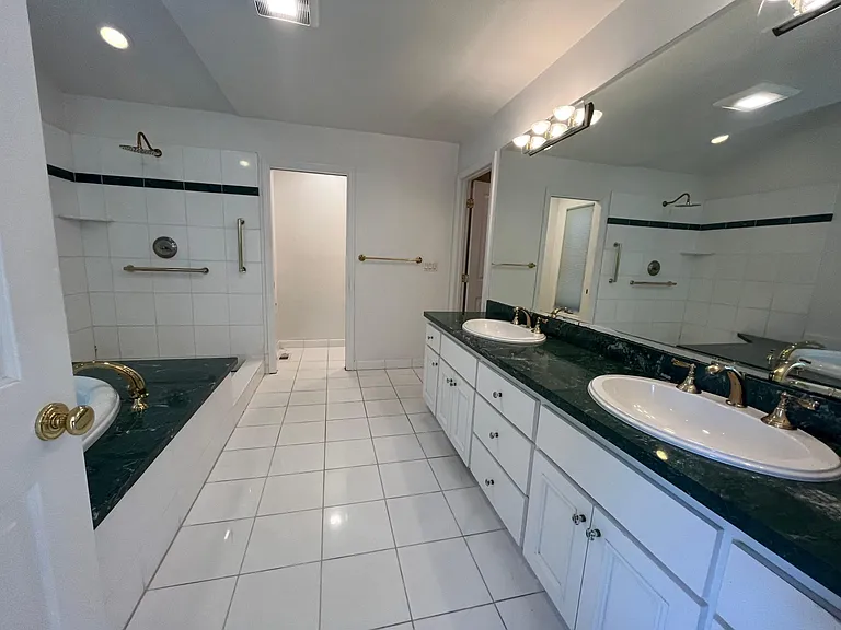 In-suite primary bathroom is tastefully-appointed with dual sinks, Jacuzzi tub and shower stall.