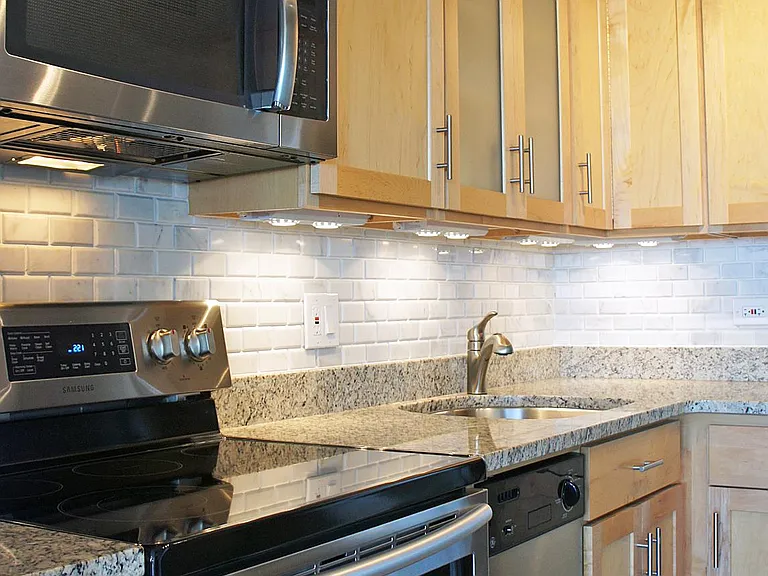 undercabinet lighting and stone floors enhance the light wood kitchen.