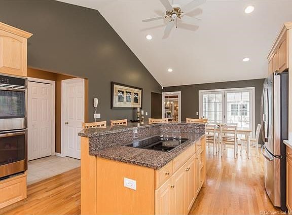 Center island with granite counters and new cooktop, double-ovens, and refrigerator. (Cook-top is vented.)