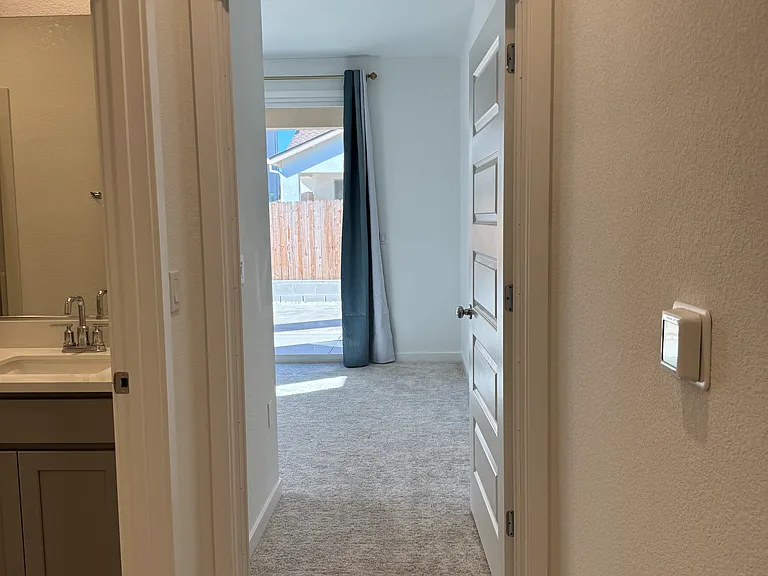 Front view of bedroom. HVAC thermostat controls on the right wall which is also app accessible.