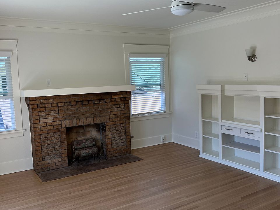 spacious living room with fireplace, new windows, blinds, ceiling fans and built ins
