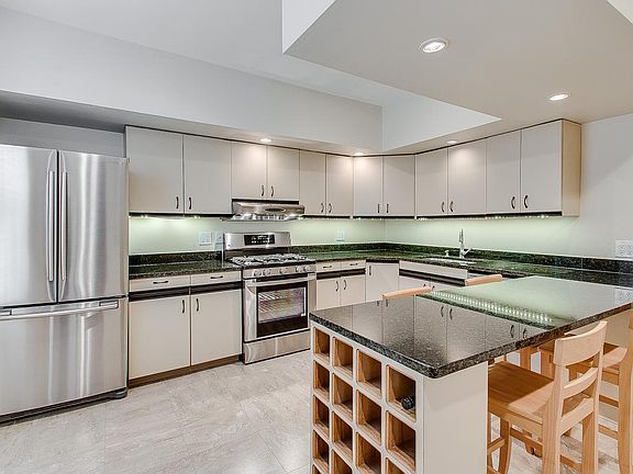 Kitchen with stainless steel appliances and wine storage under granite counters