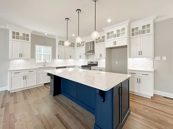 Kitchen with white quartz countertops, white cabinetry, and center island with blue cabinets.