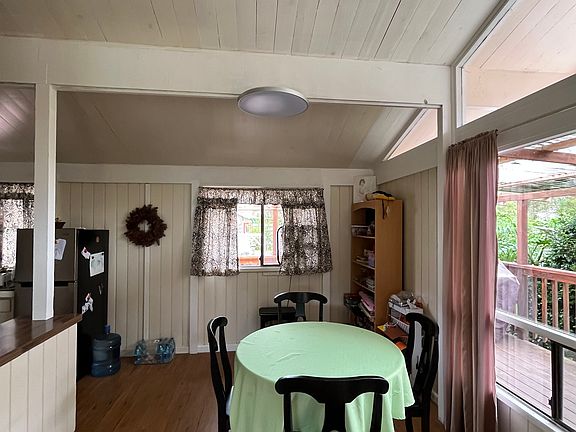 Dining table adjacent to living room and kitchen. Large windows look out to the front garden.