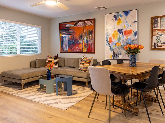 Great room with a West Elm, velvet, L-shaped couch, and a new, large Roku TV.