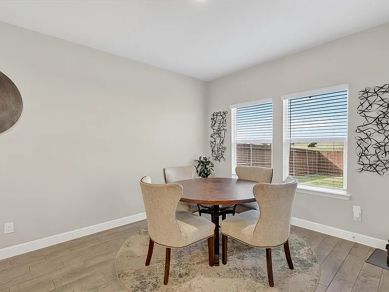 Dining area featuring two large windows, wood-finish flooring, light neutral wall paint, and white baseboards