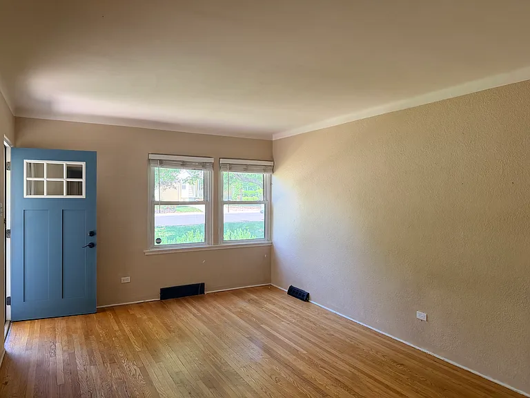 The Front door features a covered porch and opens to a sunny living room with hardwood floors and updated electrical outlets.