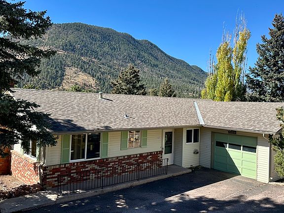 Back of home with gorgeous mountain backdrop, and large drive-way, garage and main entrance.
