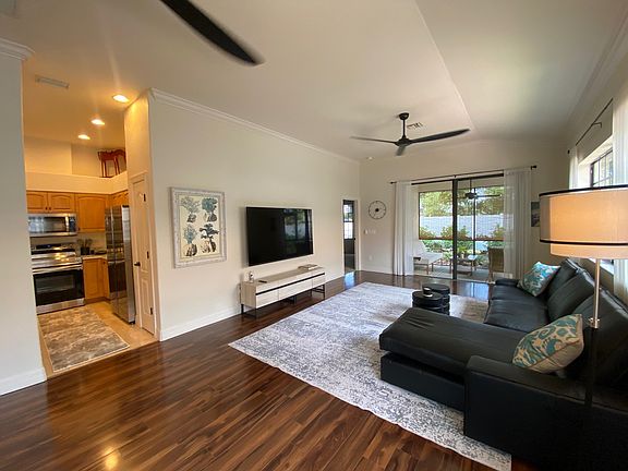 Living room with ceiling fans, high ceilings and open to kitchen