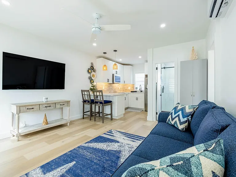 Open-concept living area with wall-mounted TV, comfortable seating, and a breakfast bar that flows into the kitchen.