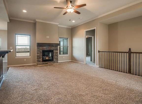 Great room offers 10' ceilings, stone fireplace surround, open stairway to the basement and opens to the kitchen and dining area.