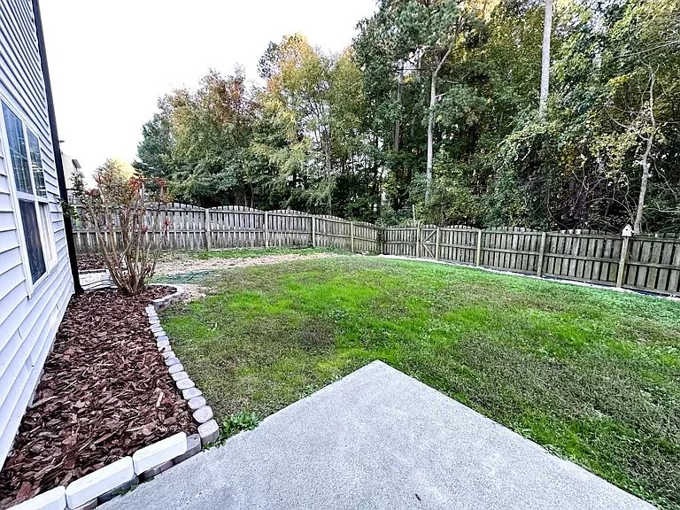 Fenced in spacious backyard with redesigned flower bed.