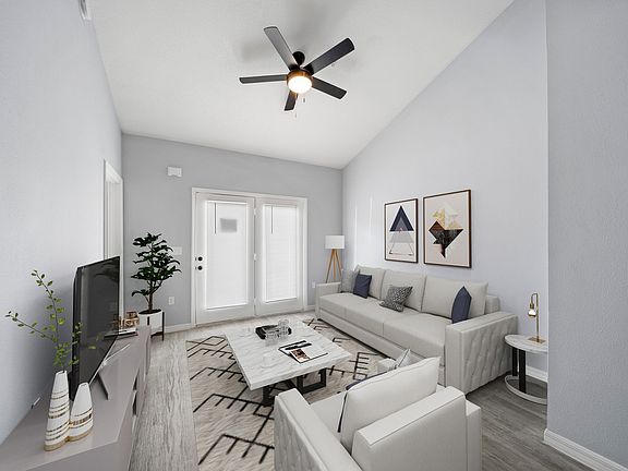 Model home living room fully furnished with double doors in view with pretty shades and a fan on the ceiling