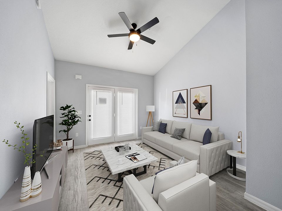 Model home living room fully furnished with double doors in view with pretty shades and a fan on the ceiling
