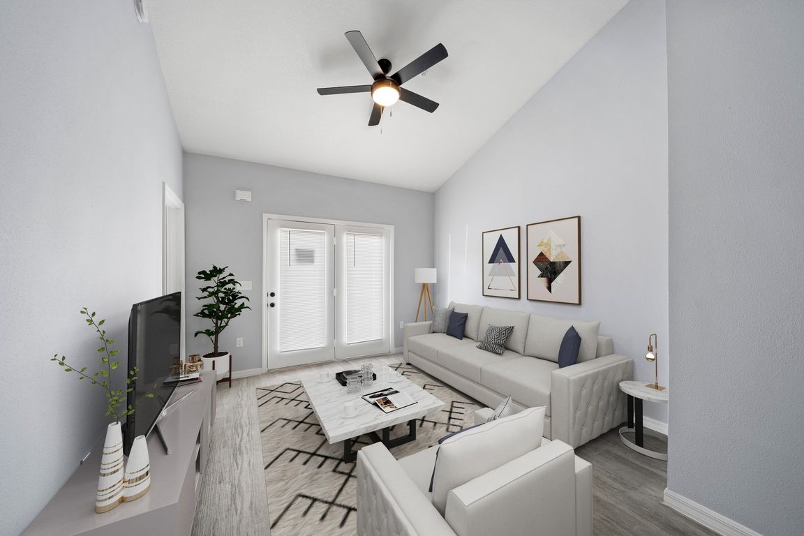Model home living room fully furnished with double doors in view with pretty shades and a fan on the ceiling