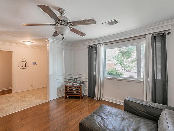 Tiled living room featuring crown molding and ceiling fan