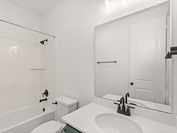 The secondary bath features tile flooring, white cabinetry and light countertops and a shower tub co