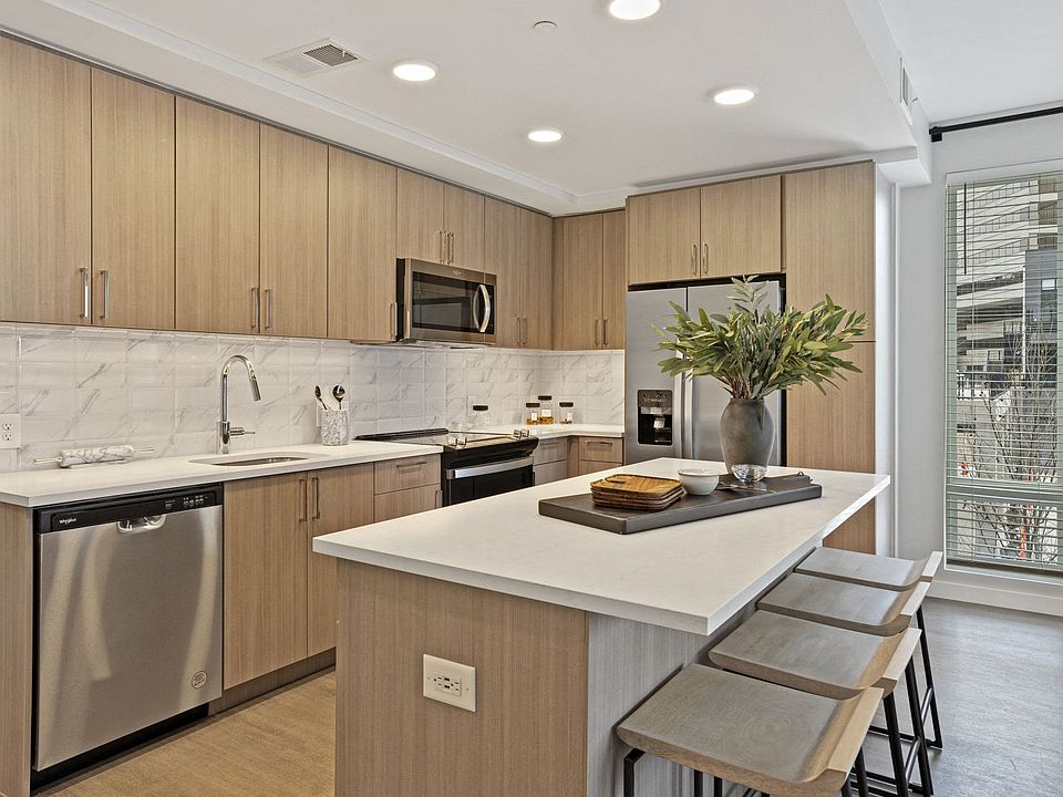 Gourmet Kitchen And Dining Area With White Countertops, Rustic Taupe Cabinets, and Stainless-Steel Appliances