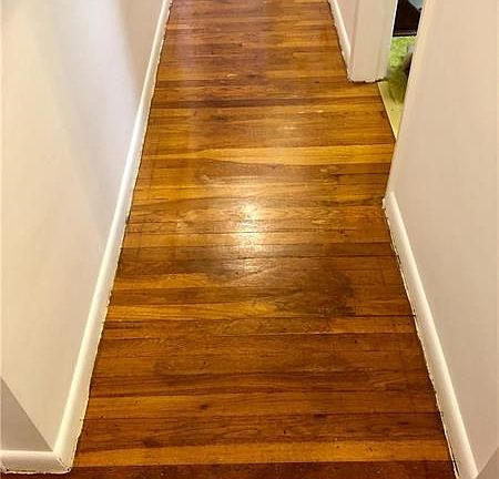 Exposed hardwood in the hall adjacent to the bedrooms.  This hardwood is under the existing wall to wall carpet.
