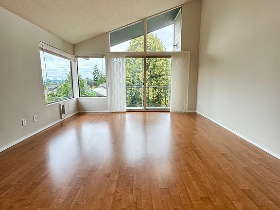 Spacious, light filled living room with vaulted ceilings and a deck/balcony