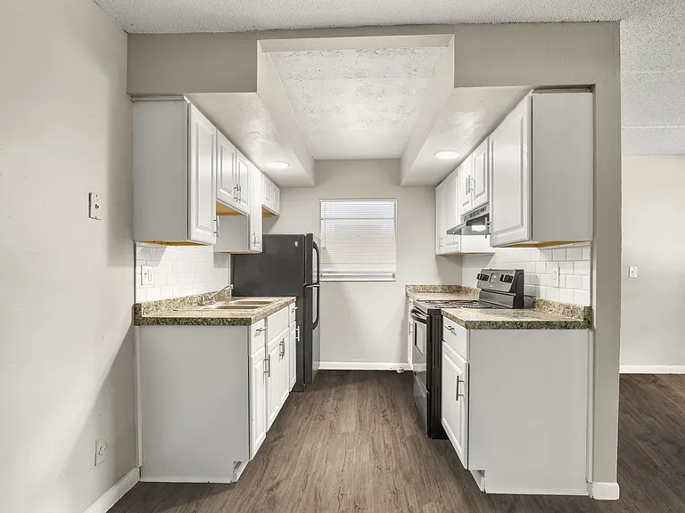 Charming kitchen with sleek black appliances, elegant white cabinets, and inviting wood flooring.