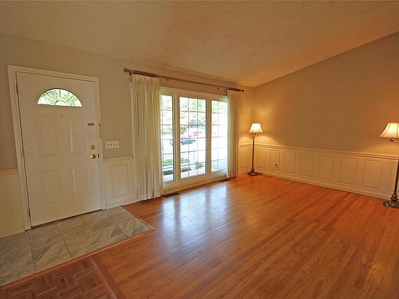 Vaulted living room with wood floors and custom wainscotting.