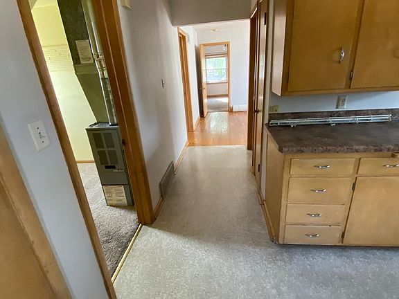 Picture shows portion of spacious kitchen with hallway leading into the living room and bedrooms. Room on the left is an extra room/office with private furnace.