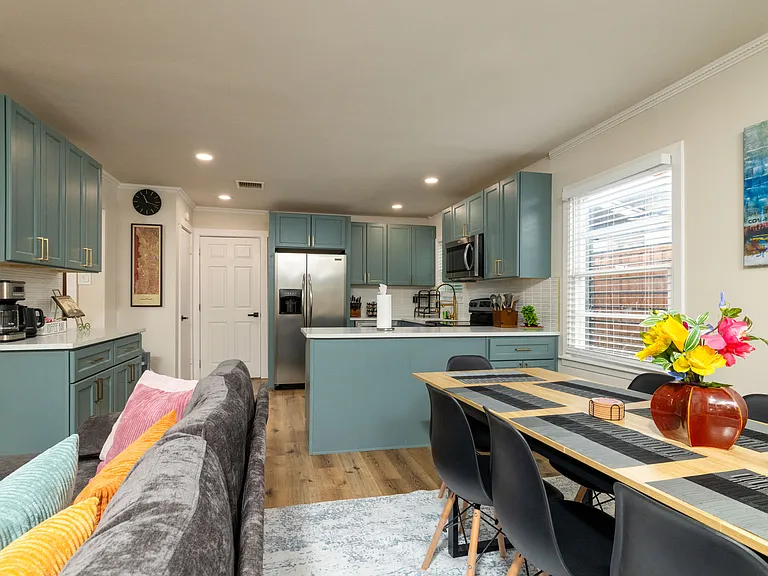 Bright dining area seating 8 with a long table for group meals, modern decor, and large windows overlooking the patio. Flows seamlessly into the cozy living room for easy gathering.