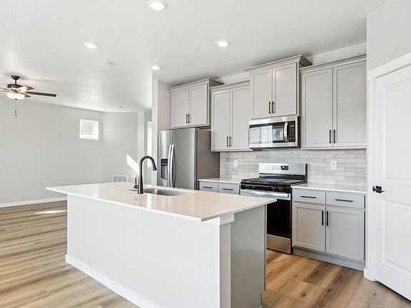 The kitchen has stainless steel appliances and plank flooring.