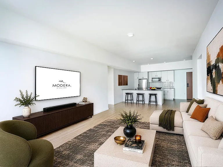 Open living area with clean-lined finishes, a generous lounge space, and a kitchen with bar seating designed for gathering and everyday comfort.
