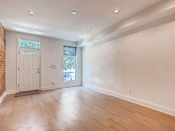 Spacious living room with exposed brick, wooden floor boards