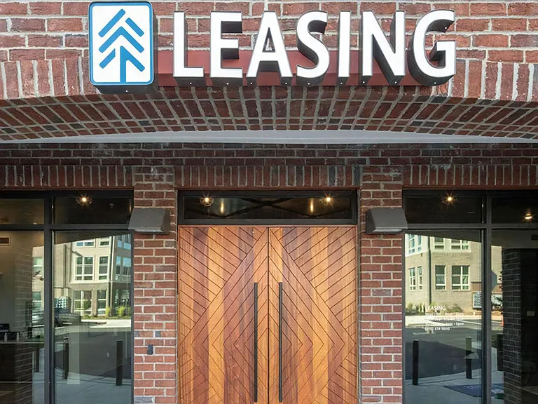 Welcoming Leasing Office Entry Framed by Large Windows and Brick Arches