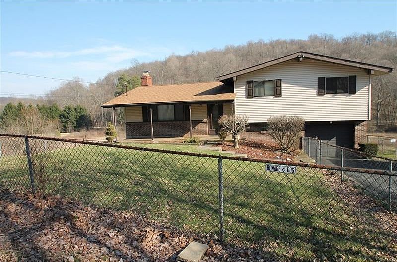 front house with fenced in yard, driveway, one car garage