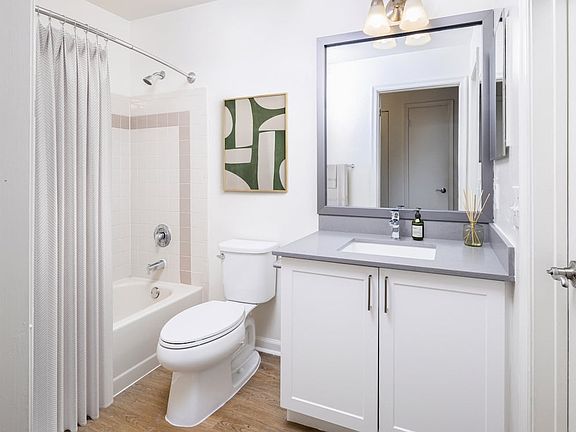 Renovated Package III bath with grey quartz countertops (select homes), white cabinetry, and hard surface flooring