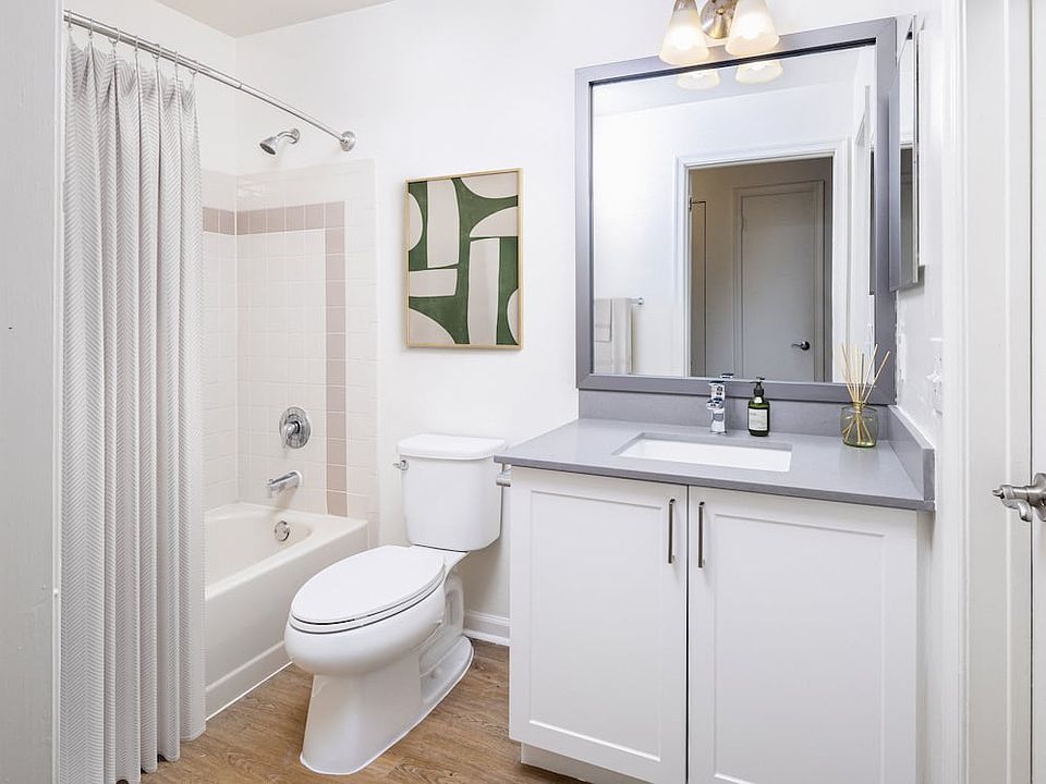 Renovated Package III bath with grey quartz countertops (select homes), white cabinetry, and hard surface flooring