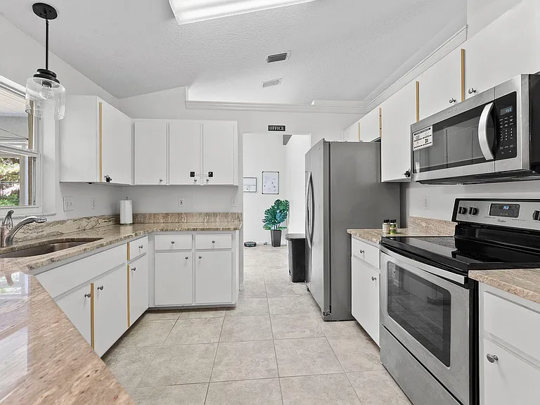 Spacious kitchen with ample cabinet storage, stone-look counters, and stainless steel range, microwave, and refrigerator.