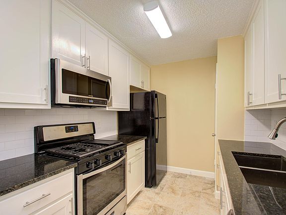 The bright kitchen comes with a fridge and the cabinets offer lots of storage space.