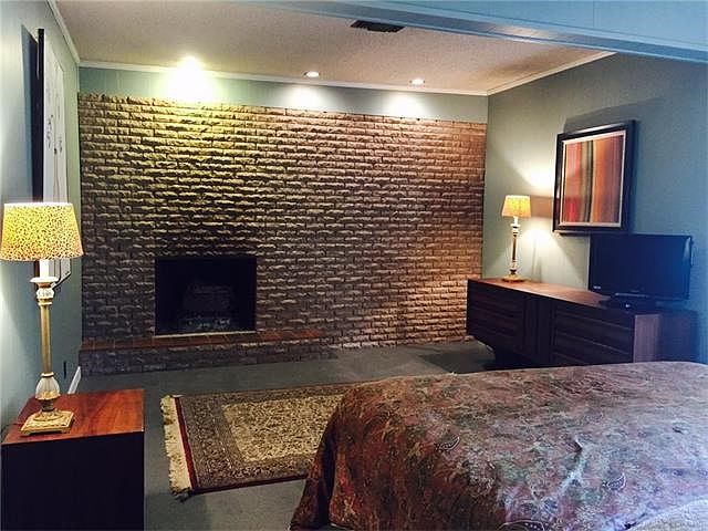 Master bedroom with recessed lighting, brick wall and fireplace!