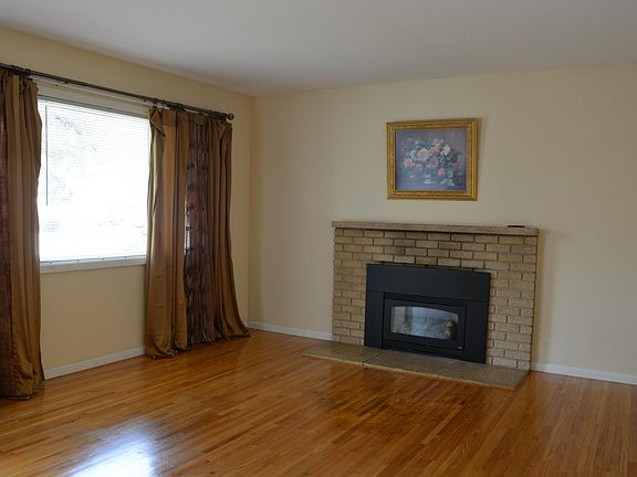 Large windows in the living room with hardwood floors and gas fireplace.