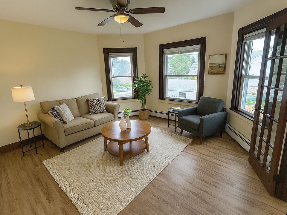 Bright living room with modern virtual staging, natural light from three windows, and French doors.