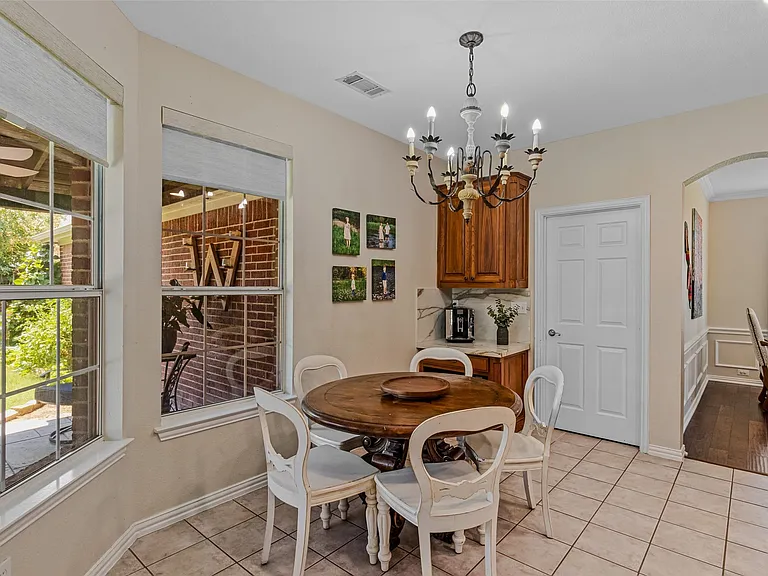 Breakfast nook featuring a decorative chandelier, ample natural light from multiple windows, a built-in coffee bar with wood-finish cabinetry, and tiled flooring