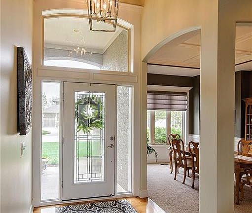Entryway is open to the second floor and features a new light fixture.  Note the leaded glass door and arched openings.