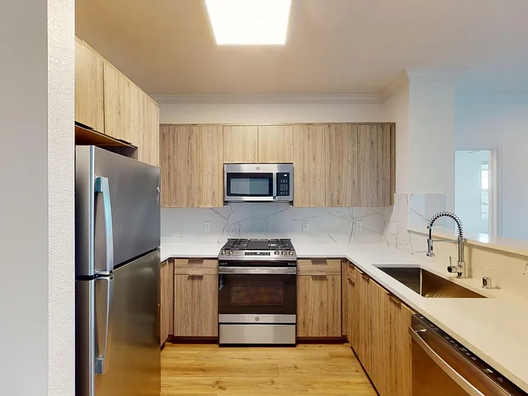 Apartment Kitchen with Quartz counter tops and Wood Style Flooring.