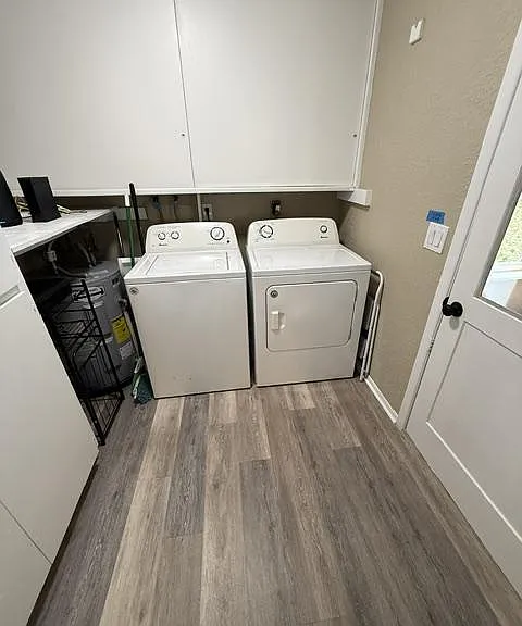 Dedicated laundry area with side-by-side washer and dryer, upper cabinets for supplies, and durable flooring.