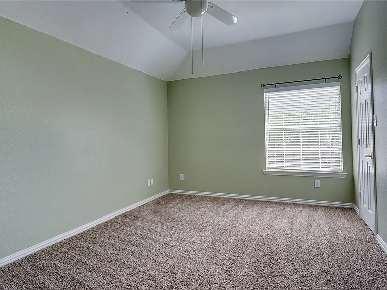Carpeted room with vaulted ceiling and a ceiling fan
