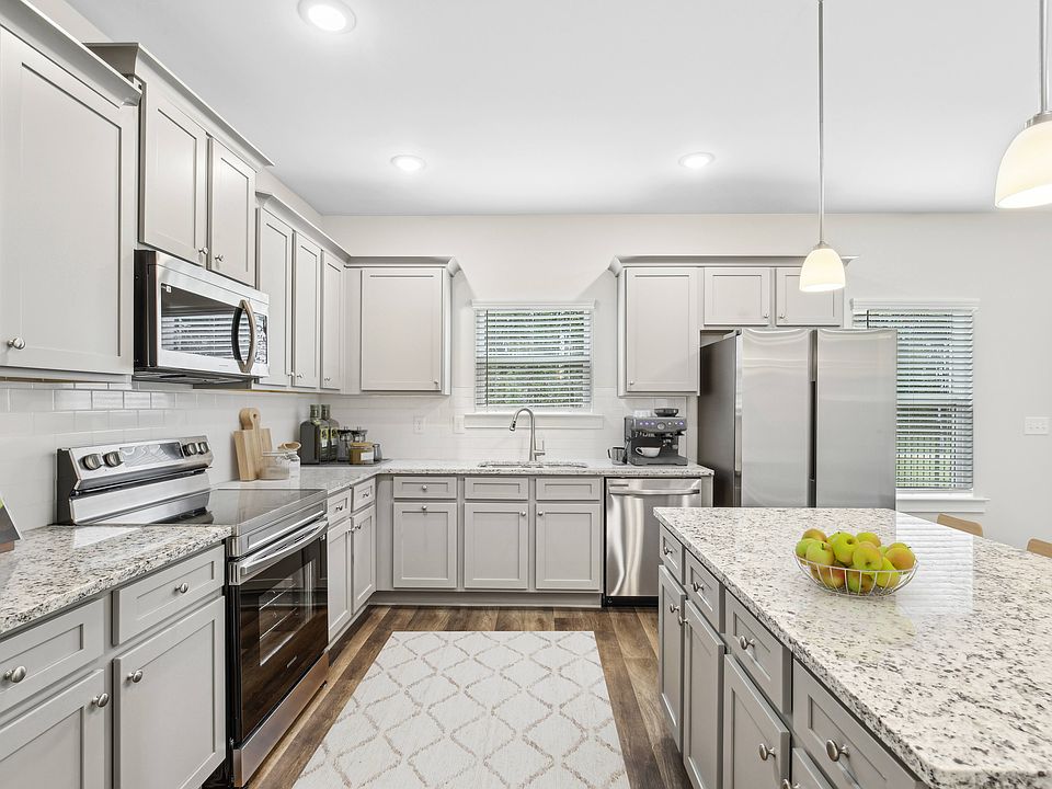 Spacious kitchen with an island, ample storage, stainless steel appliances and view into the living room.