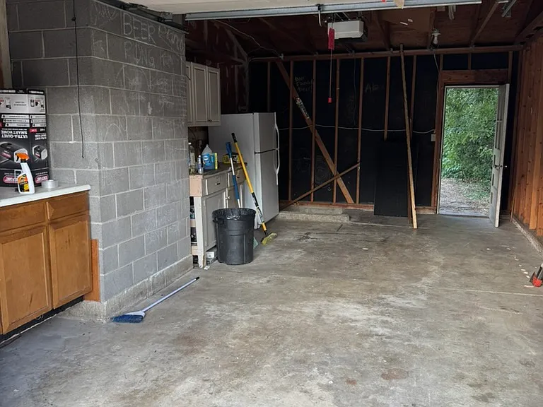 one car garage with second fridge, counter, and cabinets
