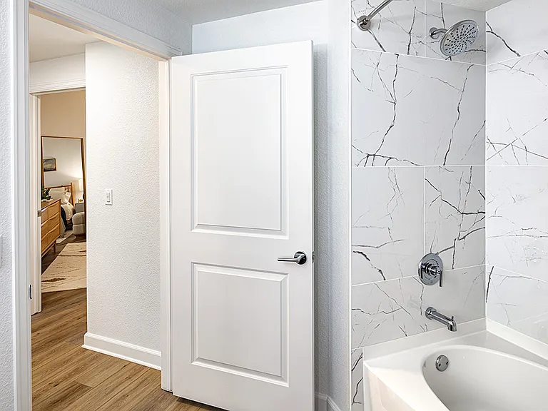 Apartment bathroom with large soaking tub and wood-style flooring.