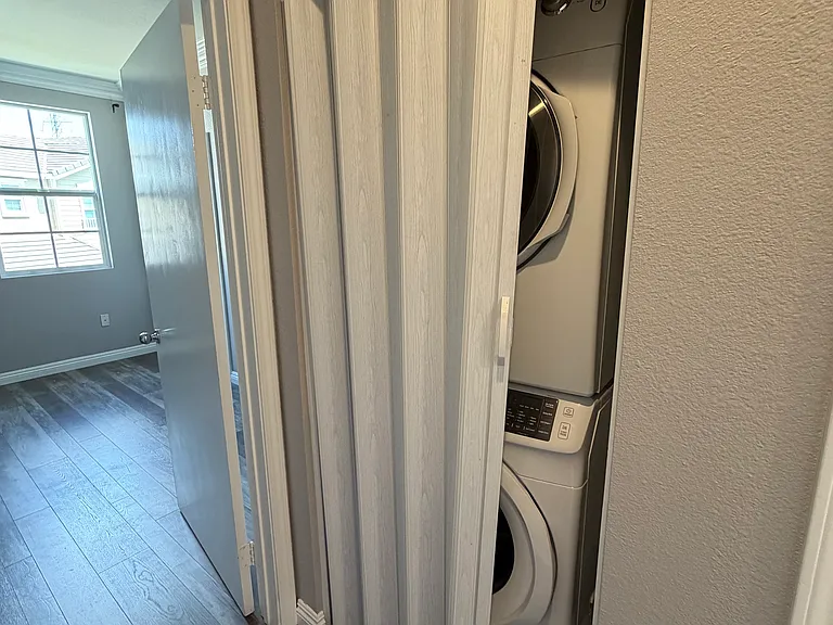 Full-size Samsung front-loading washer and dryer conveniently tucked behind bi-fold doors.