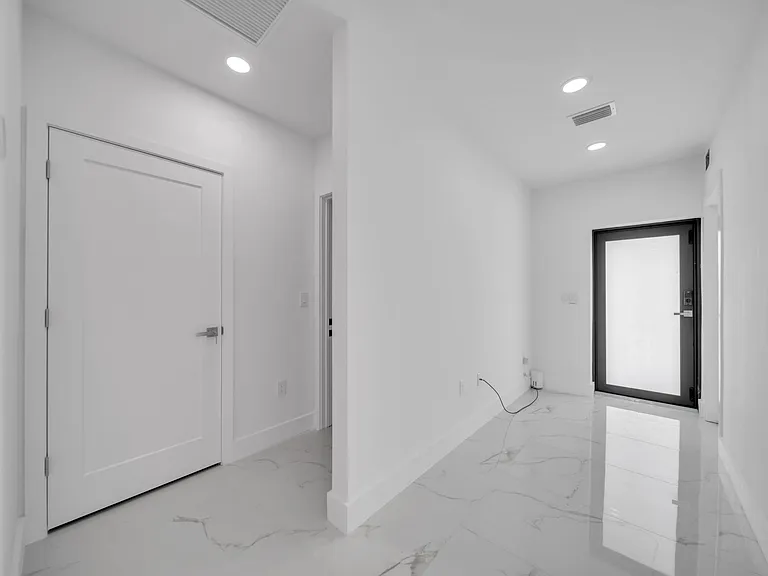 Clean entry hall with glossy tile floors, recessed lighting, and a frosted-glass exterior door for added privacy.